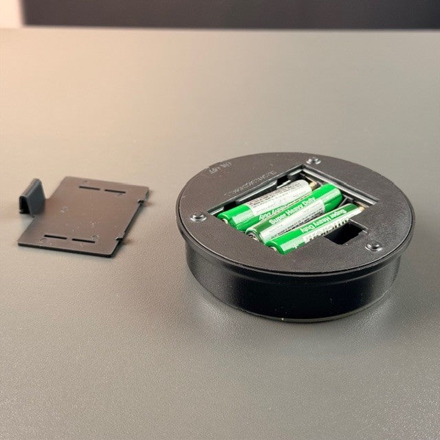 Battery compartment with three batteries in a black round light base