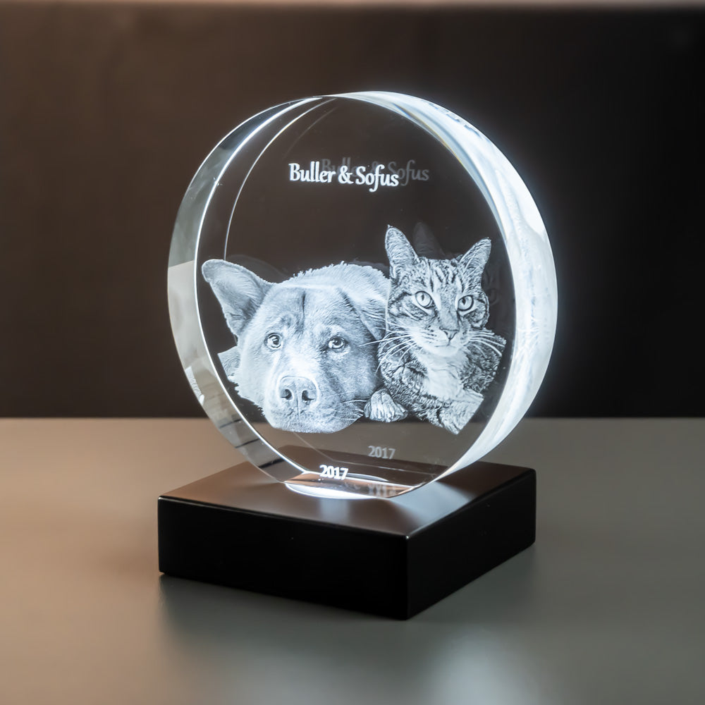 Round glass block with dog and cat seen at an angle on a matte black luxury light base