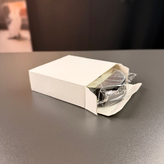 Black round battery light base in a white box