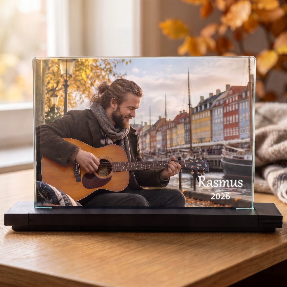 Krystal-fotoramme med farvetryk af mand med guitar ved Nyhavn og tekst, på sort fod