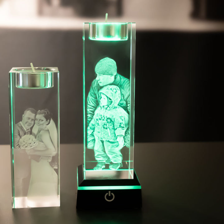 Two tea light holders with engraved motifs, one lit green by a light base
