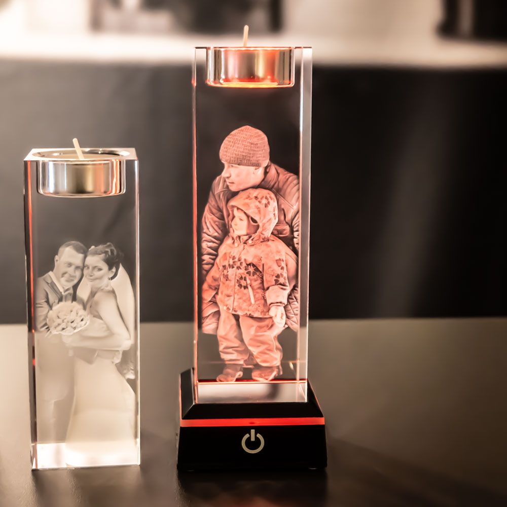 Two tea light holders with engraved motifs, one lit red by a light base