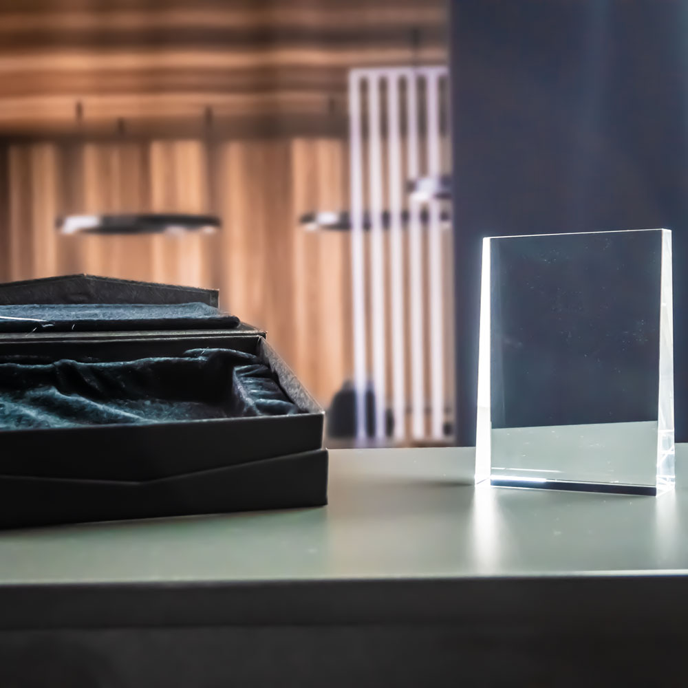 Prism award in clear crystal glass in front of the open black gift box