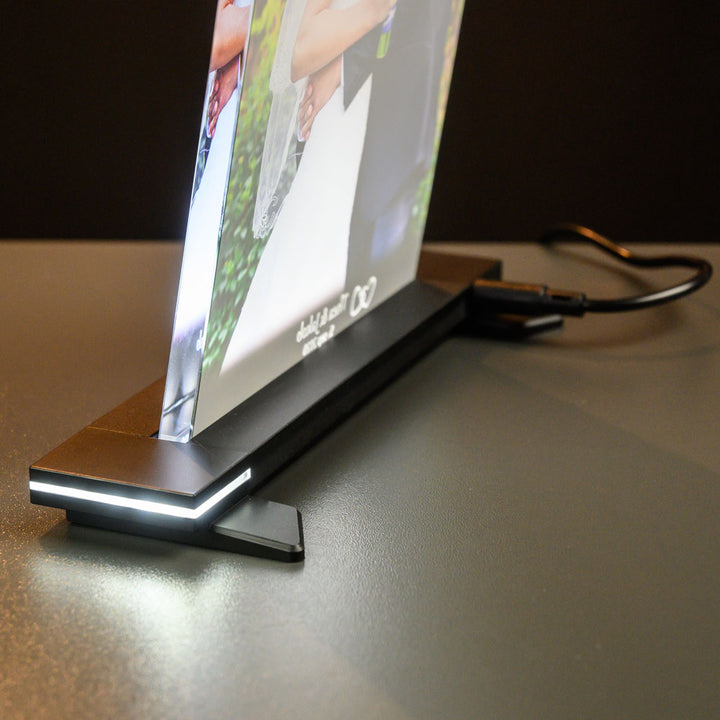 Crystal photo frame with colour print on a black light stand, seen from the side